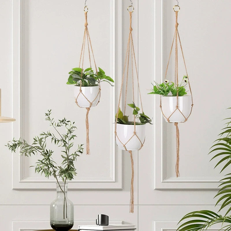 Three macrame plant hangers at staggered heights in front of a bright indoor window