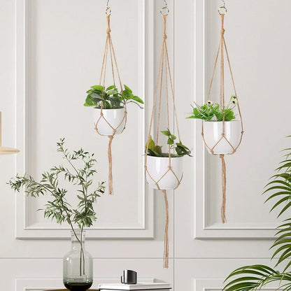 Three macrame plant hangers at staggered heights in front of a bright indoor window