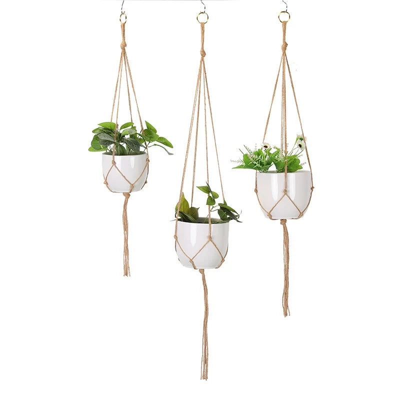 Set of 3 macrame plant hangers in natural jute-tone rope holding white pots, on a white background